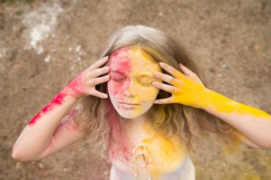 gür saçları parlak bir kız gülümsüyor, saç, yüz ve eller Holi renklerde 