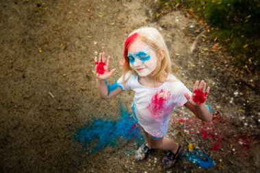 parlak kız gülümsüyor, onun yüzünü ve ellerini renkli Holi 