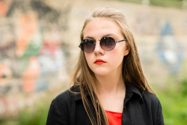 Hermosa chica con pelo largo en gafas de sol con bolsa en ropa larga y oscura — Foto de Stock
