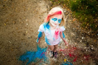 parlak kız gülümsüyor, onun yüzünü ve ellerini renkli Holi 