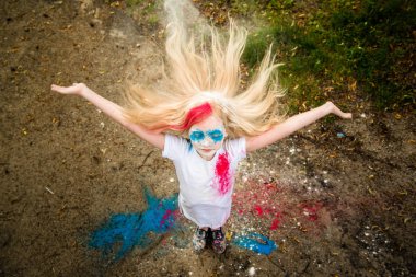 parlak kız gülümsüyor, onun yüzünü ve ellerini renkli Holi 