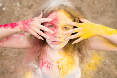 gür saçları parlak bir kız gülümsüyor, saç, yüz ve eller Holi renklerde 