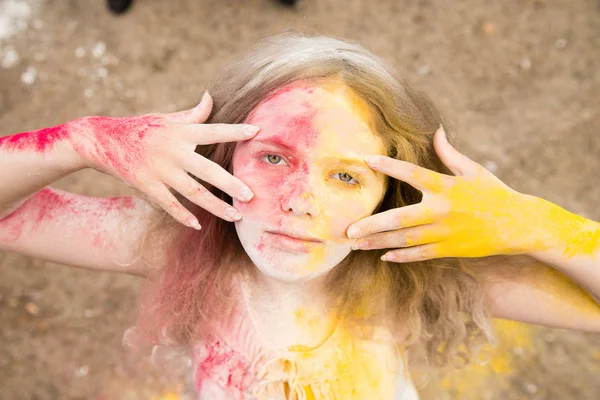 stock image a bright girl with lush hair smiles, her hair, face and hands in the colors of Holi 