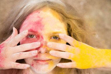 gür saçları parlak bir kız gülümsüyor, saç, yüz ve eller Holi renklerde 