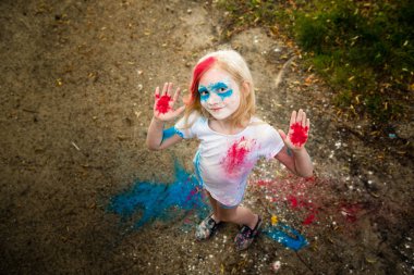 parlak kız gülümsüyor, onun yüzünü ve ellerini renkli Holi 