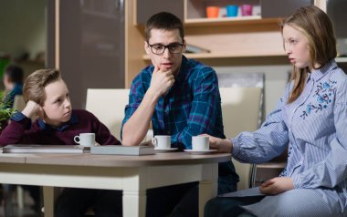 Genç bir adam, bir erkek ve kız masada oturan ve söz