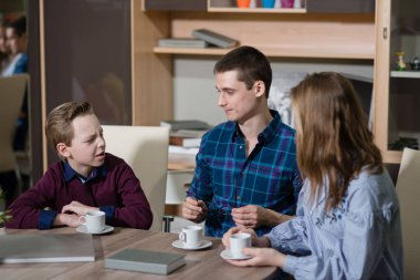 Genç bir adam, bir erkek ve kız masada oturan ve söz