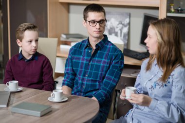 Genç bir adam, bir erkek ve kız masada oturan ve söz