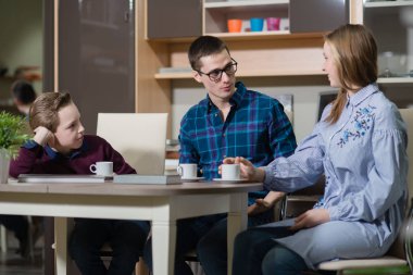 Genç bir adam, bir erkek ve kız masada oturan ve söz