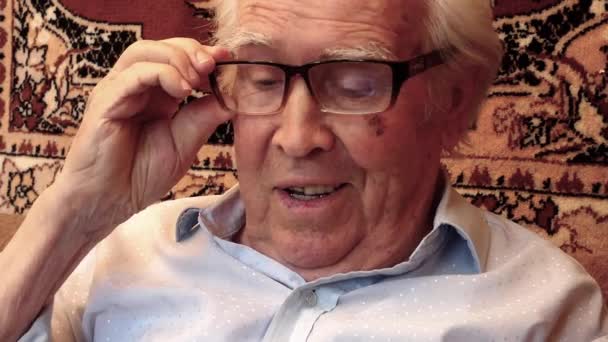 Starszy Mężczyzna Okularach Siedzi Fotelu Tle Biblioteki Przegląda Coś Laptopie — Wideo stockowe