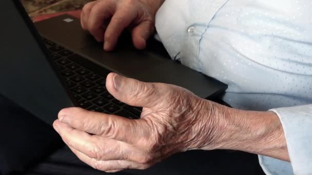 Die Hände eines sehr alten Mannes arbeiten mit einem Laptop. Nahaufnahme.