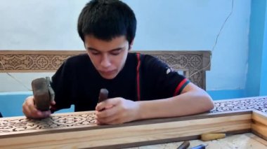 Tahta ürünler üzerinde ulusal şablon oymacısı. Genç bir usta doğuya özgü bir model yaratmaya çalışıyor..