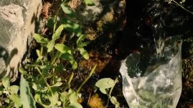 Dağ pınarı. Kayaların arasındaki yarığa bir tüp yerleştirilir ve bu yarıktan kaynak suyu akar. Altta su toplamak için yarım bir plastik şişe var..