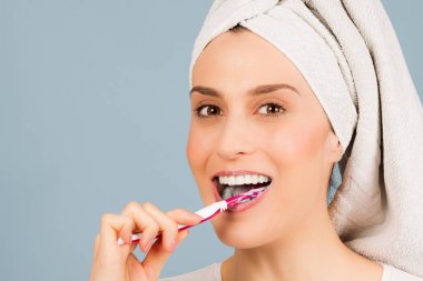 Kafa havluya güzel kadınla parlak mavi zemin üzerine beyaz dişlerini fırçalıyor.