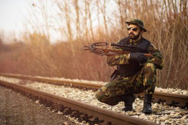 Tatar yayı silah ile askeri üniformalı ordu asker rayların üzerinde açık havada olduğunu.