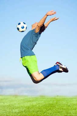 Futbol oyuncusu atlama ve topu göğsünde hava, futbol eylem, spor hareket ile çekim.