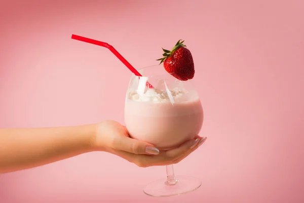 女性手拿着美味的健康草莓奶昔饮料与生奶油在明亮的粉红色背景 — 图库照片