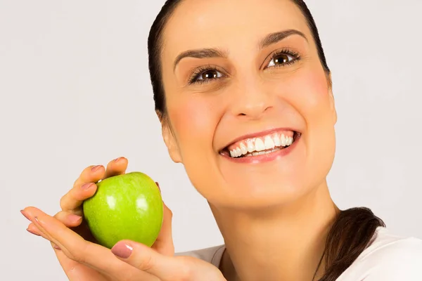 美丽的微笑妇女与白色健康的牙齿是持有一个绿色的苹果在白色背景 工作室拍摄 医疗保健和牙科护理的概念 — 图库照片