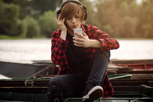 Genç çocuk kulaklık ile müzik göl kenarında açık havada.