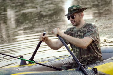 Oarsman göl kenarında şişme botla kürek.