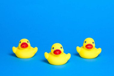 Üç sarı sevimli banyo ördek oyuncak üzerinde mavi arka plan vardır.