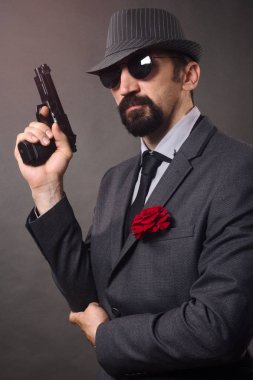 Eski moda şık erkek takım elbise, şapka ve güneş gözlüğü elinde bir tabanca tutuyor.