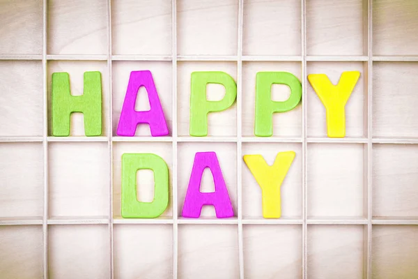 Happy day text from colorful letters is on wooden board.
