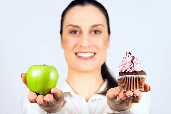 微笑的女人可以选择决定苹果或纸杯蛋糕 健康或不健康的饮食 — 图库照片