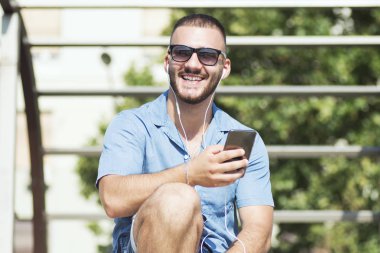 telefon kullanarak gülümseyen genç adam