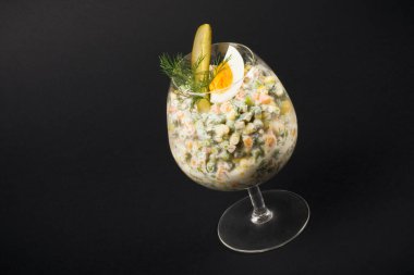 Rus salatası, siyah arka planda bardakta servis edilir..