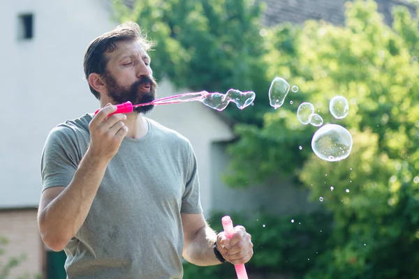 Vousatý Muž Fouká Mýdlové Bubliny Bublinkovou Hůlkou Venku — Stock fotografie