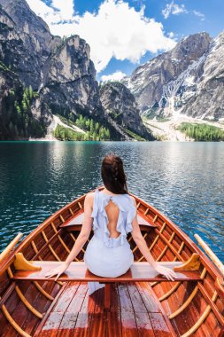Lake Braies, İtalya. Elbiseli bir kız bir tekne içinde oturur. Güzel dağ manzaralarına sahiptir