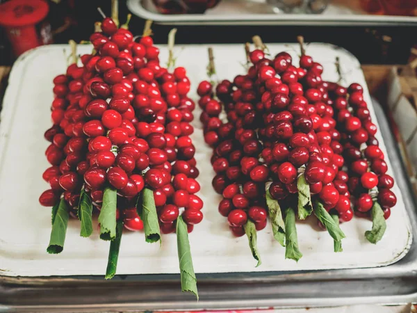 Red ripe tkemali plums on grape leaves at georgian market — Stock Photo