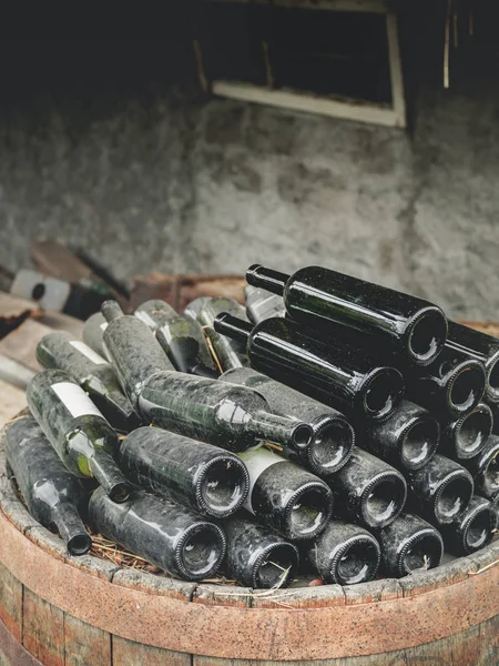 Empty dirty used wine bottles on pile in wooden barrel in georgia — Stock Photo