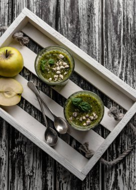 Delicious green smoothie in glasses on rustic wooden board clipart