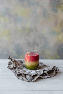 Delicious layered smoothie on rustic wooden board with napkin clipart