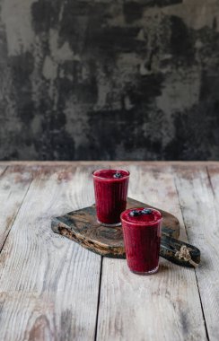 Ahşap arka plan üzerinde bardaklarda organik blueberry smoothie