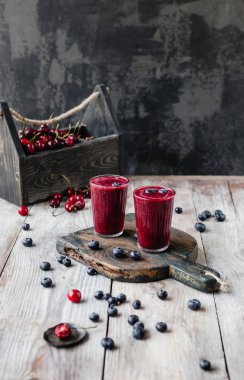 Ahşap arka plan üzerinde bardaklarda organik berry güler yüzlü