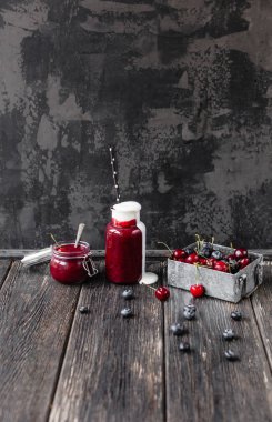 Şişe ve kavanoz ahşap arka plan üzerinde organik berry güler yüzlü
