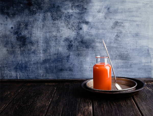 Fresh orange smoothie in bottle on rustic table