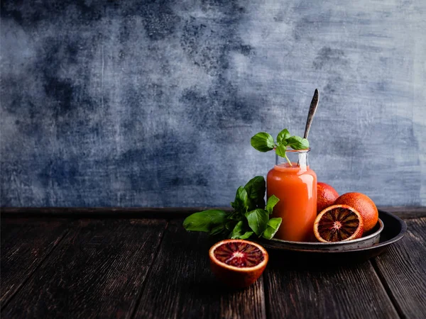 Organic orange juice with basil leaves on wooden background