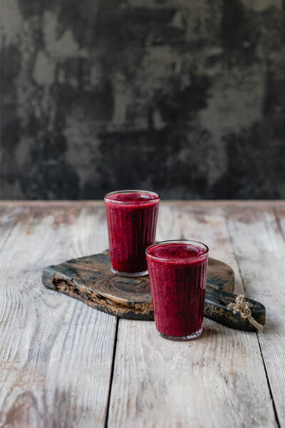 Delicious detox blueberry smoothie in glasses on rustic wooden board