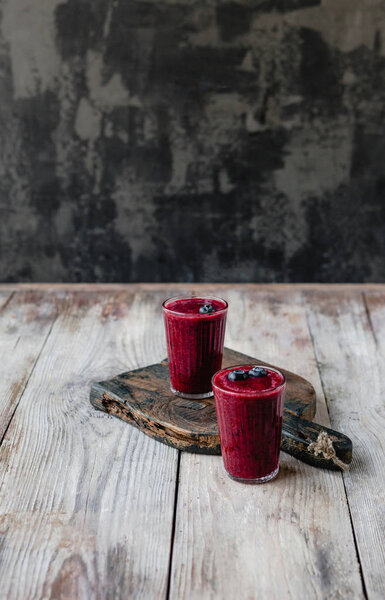 Organic blueberry smoothie in glasses on wooden background