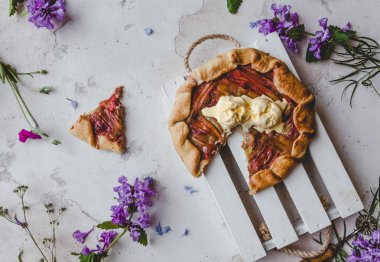 elevated view of delicious rhubarb pie on table with violet flowers clipart