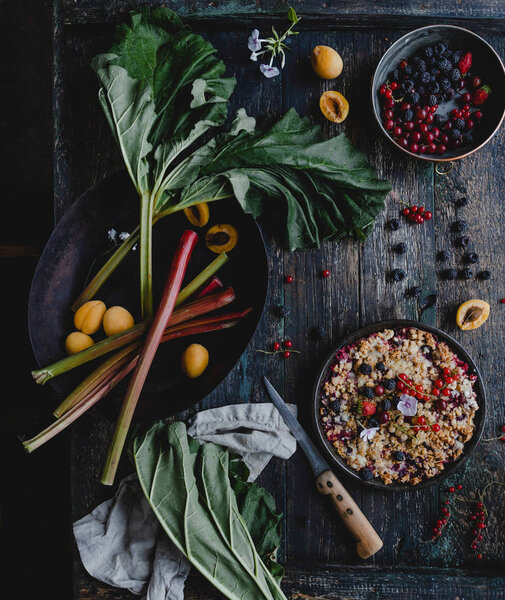 elevated view of appetizing pie with berries and rhubarb on wooden table