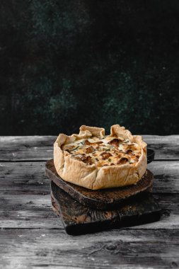 cooked appetizing pie with mushrooms on wooden table clipart