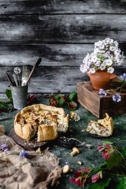yummy pie with mushrooms and potted flowers on wooden table clipart