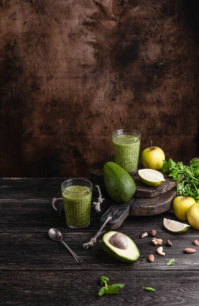 Batido ecológico sobre mesa rústica con frutas y hierbas - foto de stock