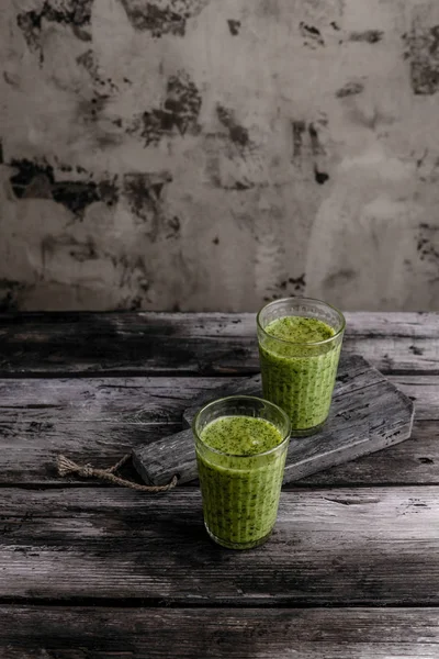 Delicious green smoothie in glasses on rustic wooden table — Stock Photo