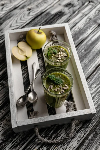 Delicioso batido de desintoxicación en vasos en bandeja de madera rústica - foto de stock